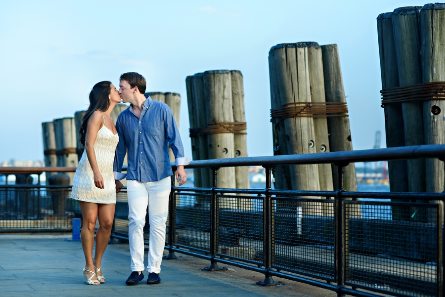 A cute couple walking along the river in battery park during their engagement session.